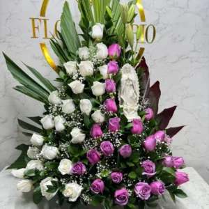 Arreglo floral funebre con rosas moradas y blancas con virgen en marmolina