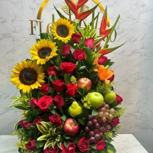 Arreglo floral con rosas, girasoles, lirios y frutas