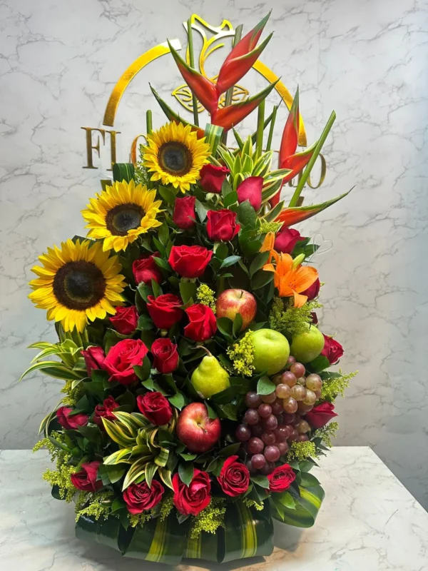 Arreglo floral con rosas, girasoles, lirios y frutas