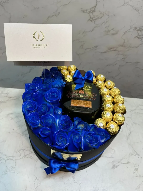 Cilindro con rosas azules, chocolates Ferrero Rocher y botella de Buchana's